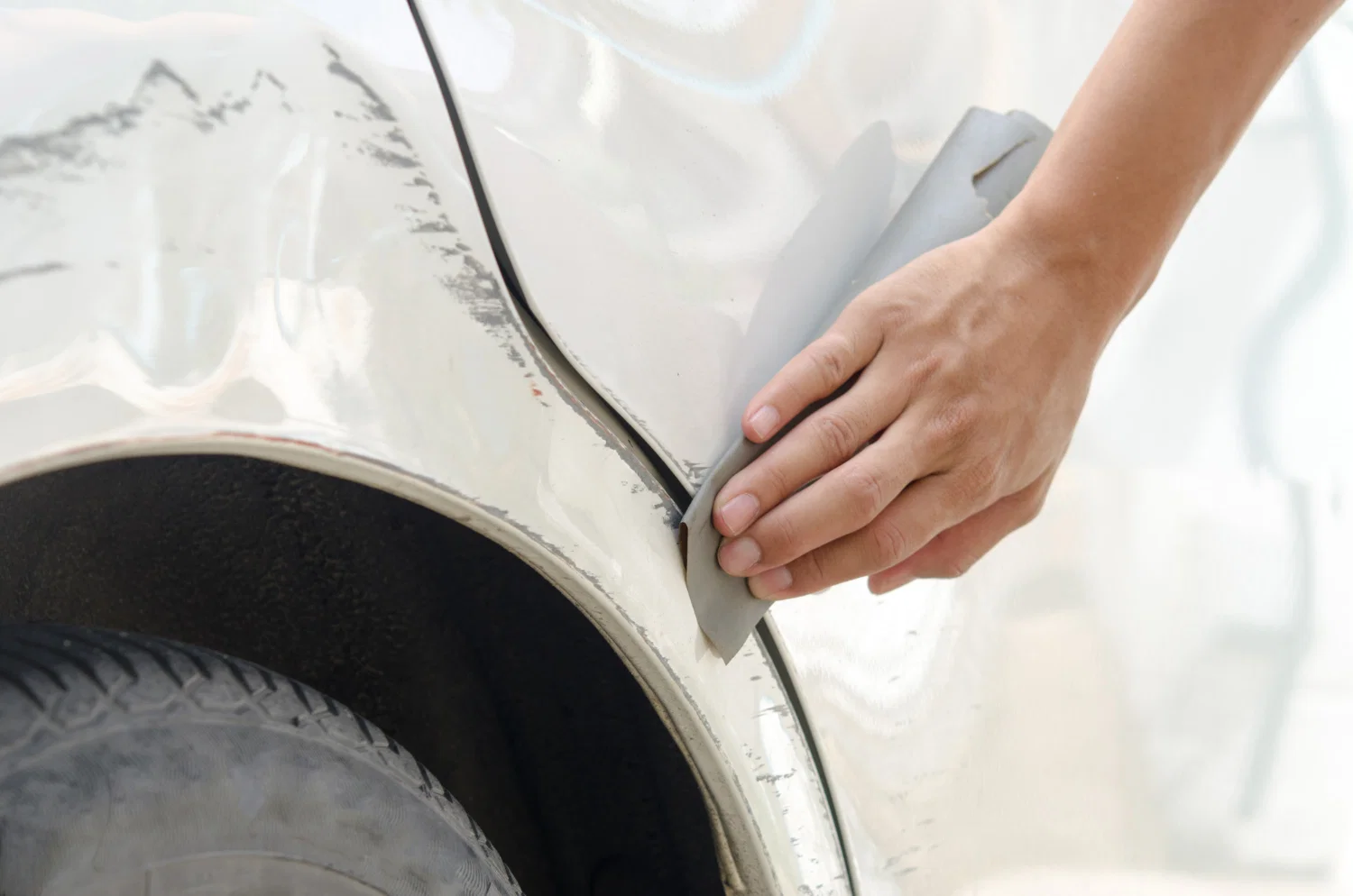 Professional dent repair and scratch repair technician working on damaged vehicle at auto body shop